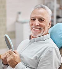 man smiling while holding dental mirror 